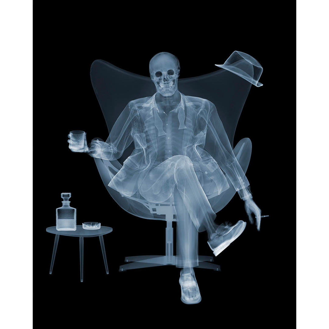 x ray skeleton photography figure sitting in mid century modern chair in suit untied relaxing with cocktail and cigarette in blue grey on black background 