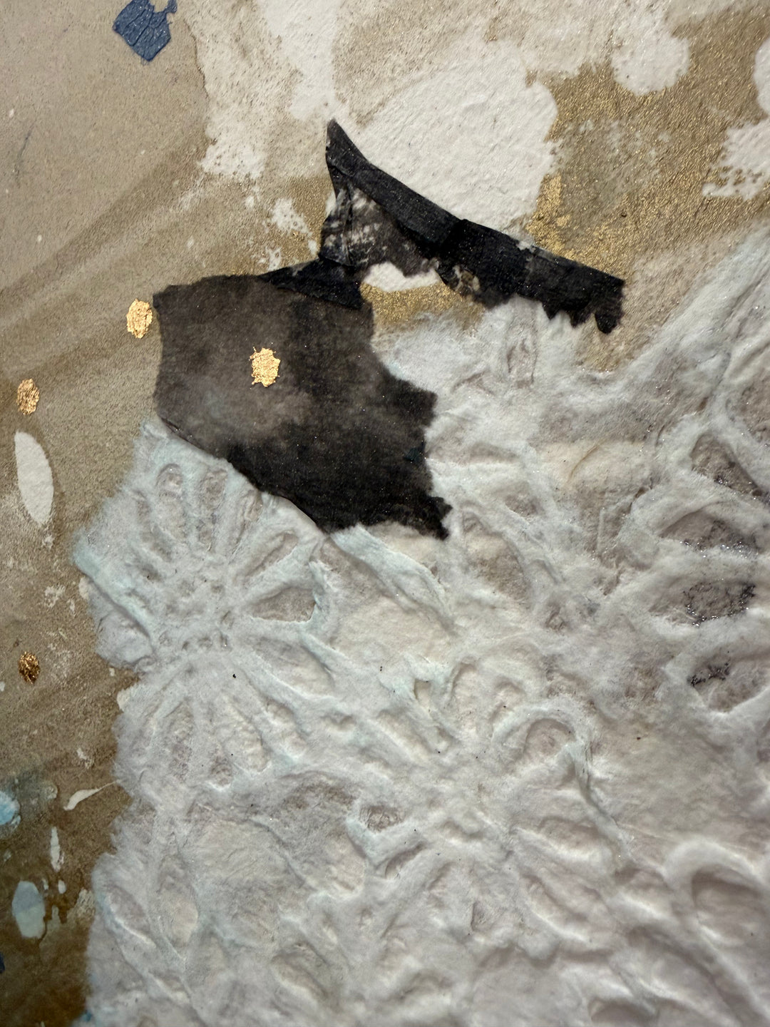 Christopher Peter, Born to Be Blue, acrylic, oil, handmade papers and gold leaf on canvas, 48 x 40 inches. Detail of the top of the head, showing a torn black paper fragment with gold leaf dots over tan and white marbled paper and white embossed floral handmade paper.
