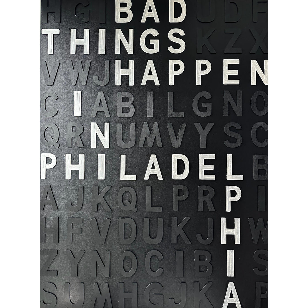 random black wooden letters are on a black canvas with white letters spelling out "Bad Things Happen In Philadelphia" mixed throughout.