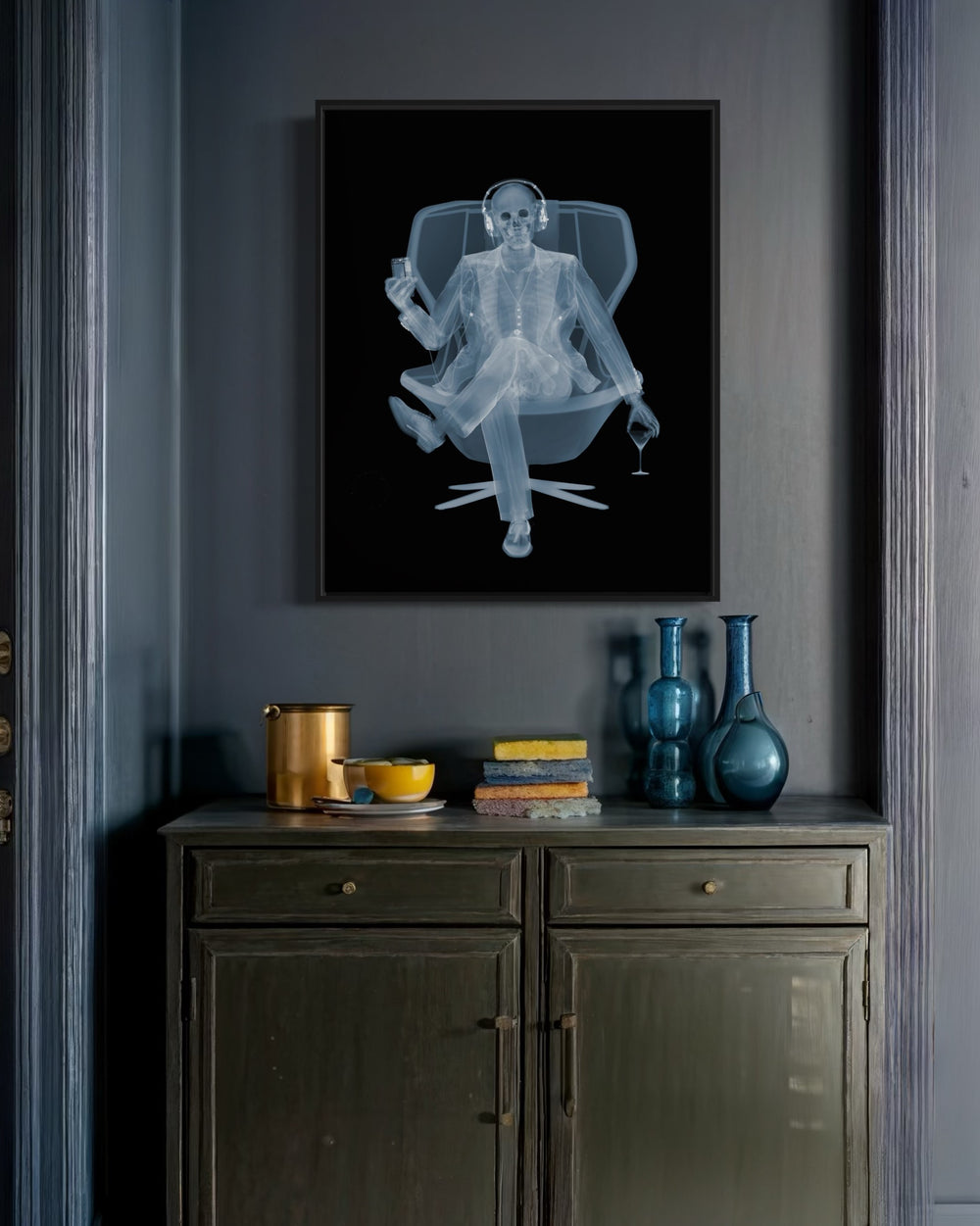 Framed Chromaluxe x-ray photograph by Nick Veasey of a skeleton listening to music with headphones in a swivel chair with a martini