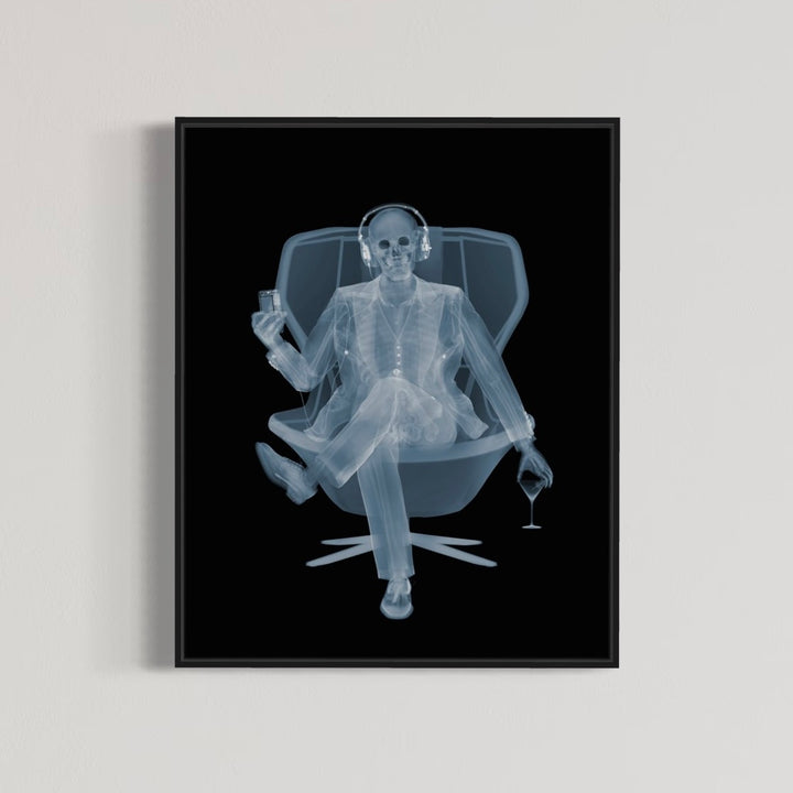 Framed Chromaluxe x-ray photograph by Nick Veasey of a skeleton listening to music with headphones in a swivel chair with a martini