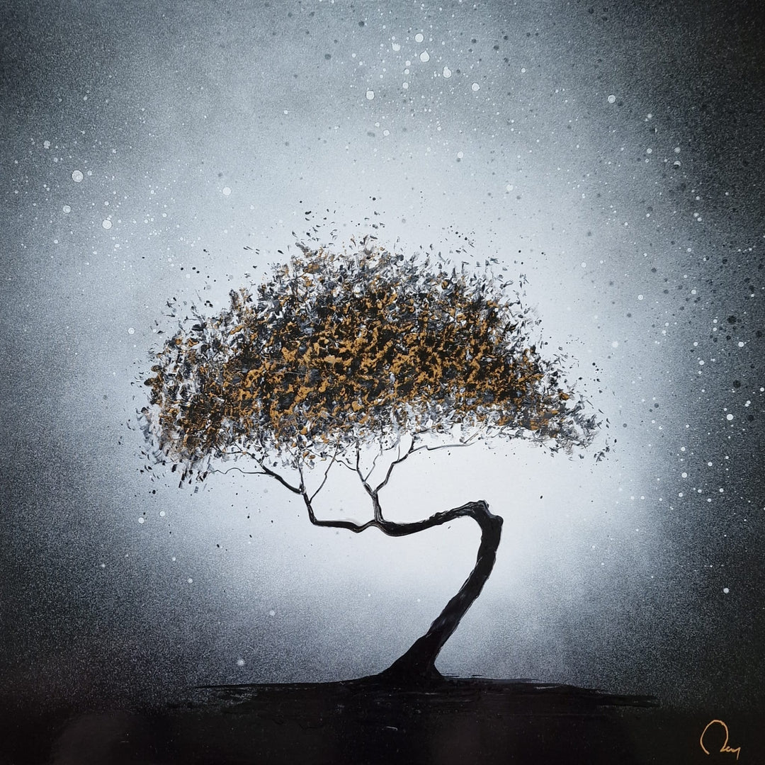 "Golden Light" by French artist Julien Rey — a mixed-media painting on board of a solitary windswept tree, crafted with Chinese lacquer and gold leaf. A dramatically curved black trunk bends gracefully beneath an expansive canopy of gold leaf and dark lacquer foliage, set against a luminous silver-gray sky dusted with delicate white droplets evoking snow or starlight. Original contemporary gold leaf tree painting on board available at Morton Contemporary gallery.