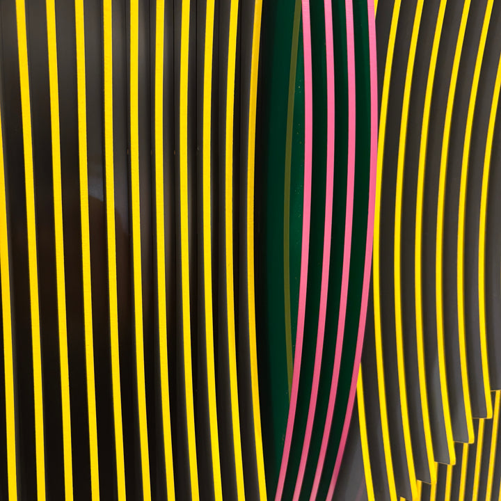 vertical stripes in black and yellow with circle in center offset optical illusion stripes with pink purple stripe down the middle