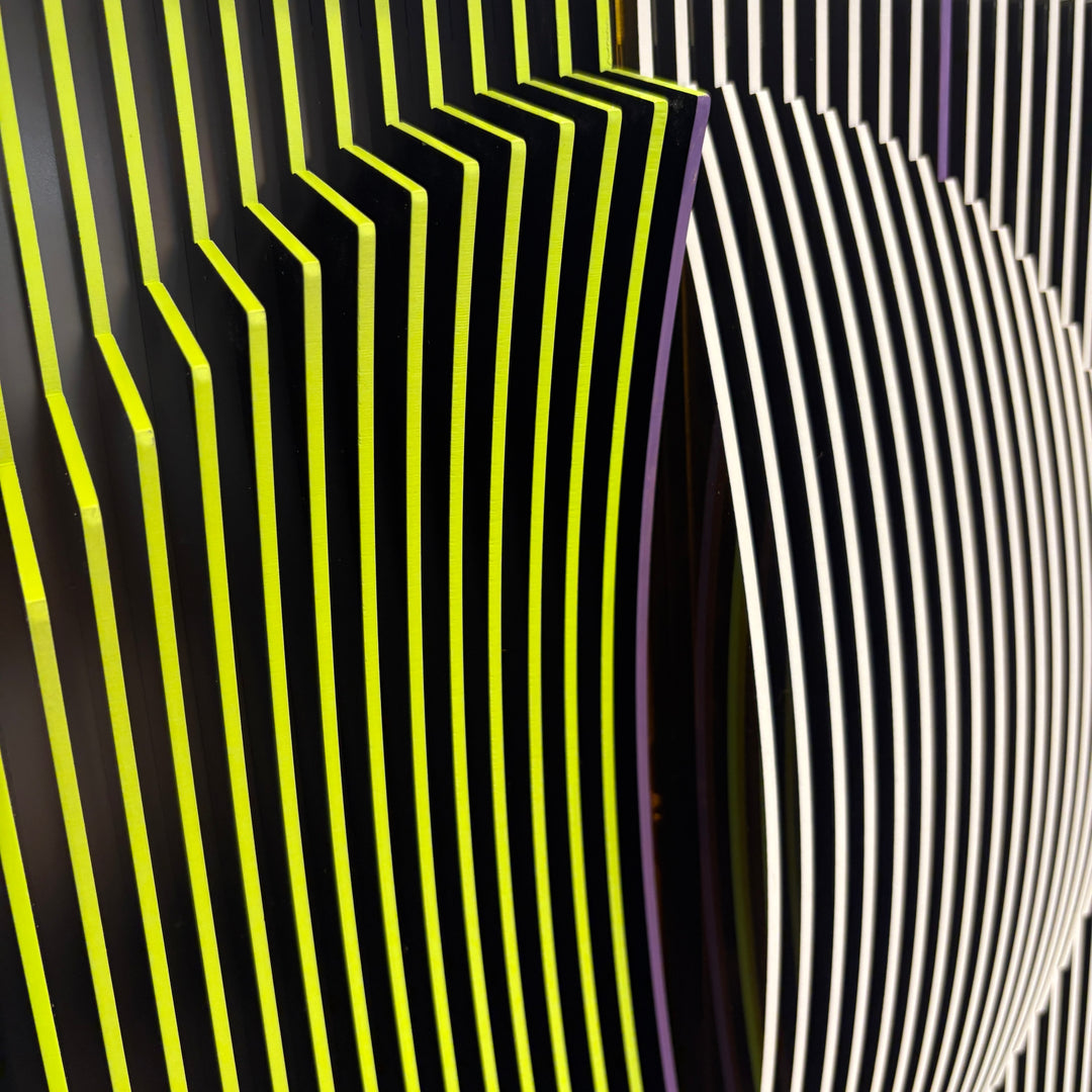 vertical stripes in black and yellow with circle in center offset optical illusion stripes with pink purple stripe down the middle