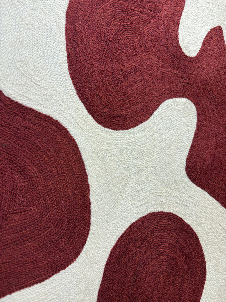 abstract shapes in rust orange red color on cream white background embroidery textile chain stitched design negative space shapes and patterns 