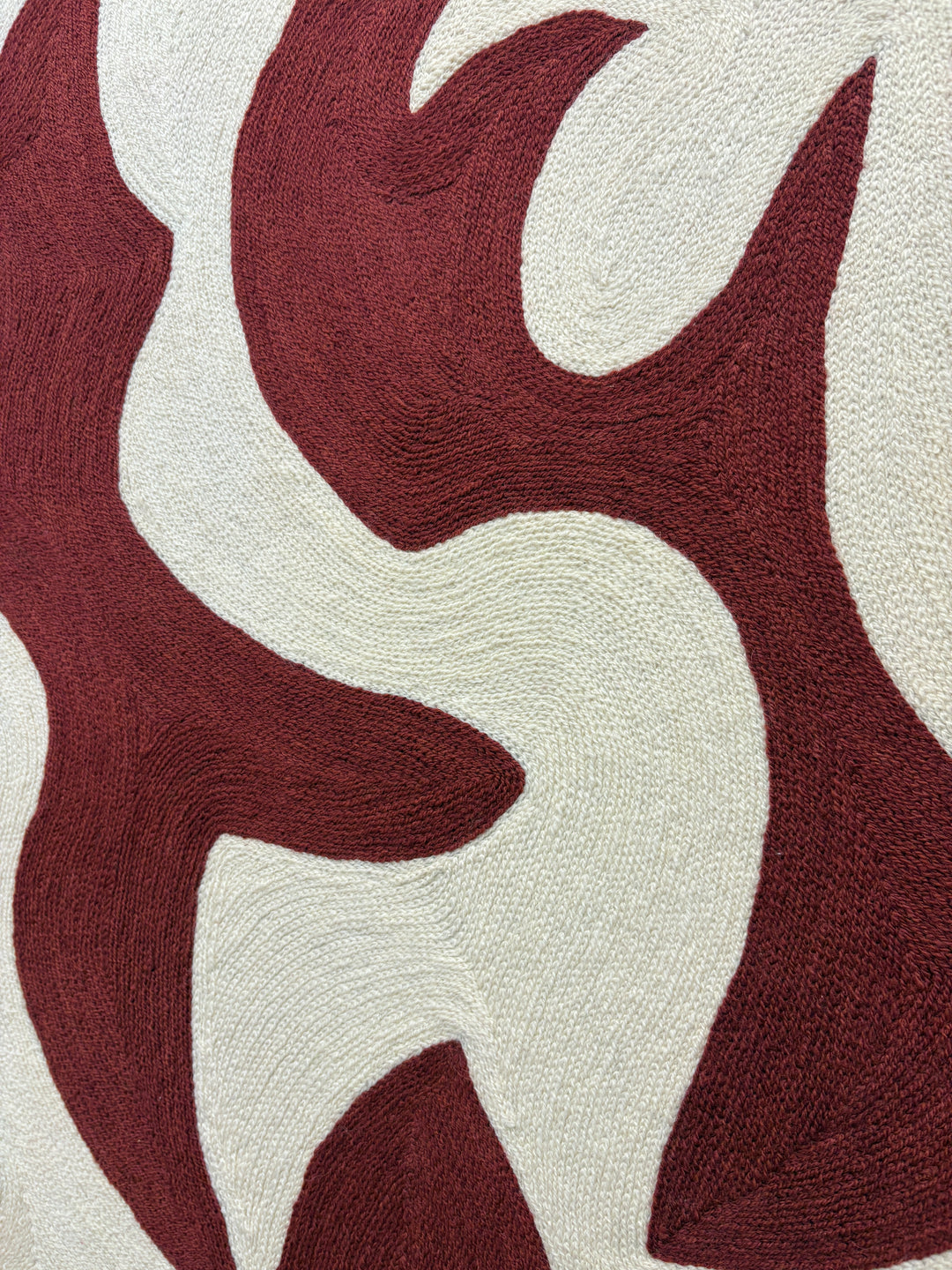 abstract shapes in rust orange red color on cream white background embroidery textile chain stitched design negative space shapes and patterns 