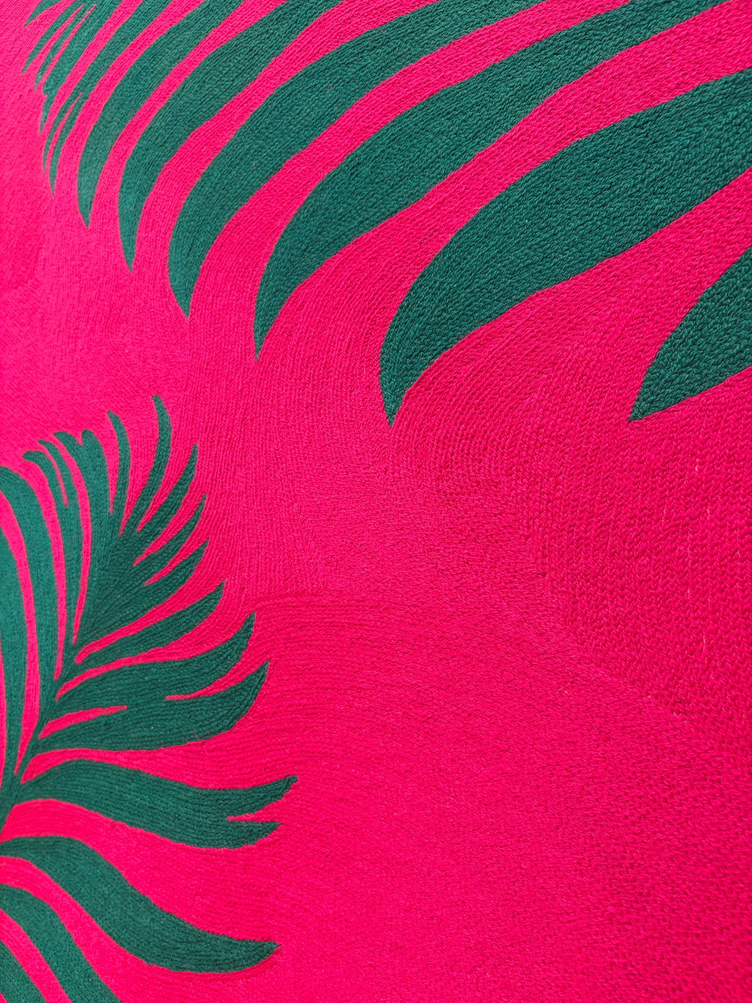 42.5"x42.5" chain-stitched textile with two tropical leafs over a bright pink background. 