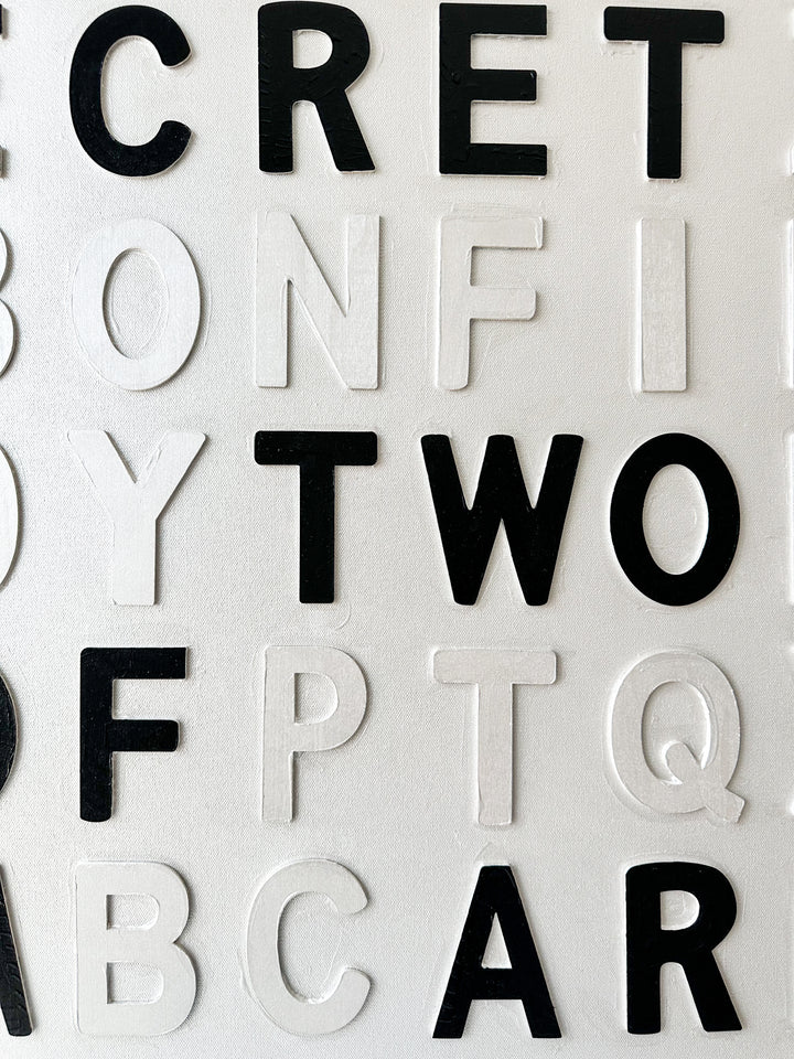 Contemporary 3D text artwork by Chicago artist Steffanie Gerkin titled Keep A Secret 3D, featuring raised black and white wood letters arranged in a structured alphabet grid on a white canvas. The typographic composition spells “Keep a Secret,” “Three May,” and “Two of Them Are Dead,” creating a bold monochrome mixed-media wall art piece with graphic, conceptual, and pop art qualities.
