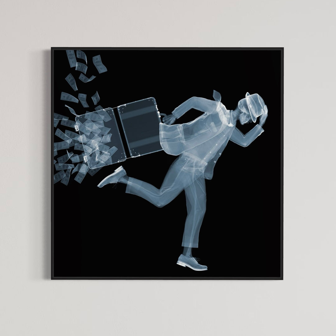 Framed Chromaluxe black and white x-ray photograph by Nick Veasey of a skeleton man in a fedora and suit running against the wind as his briefcase full of cash opens and the money blows away