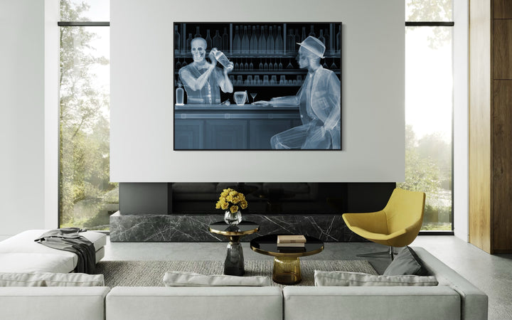 Framed Chromaluxe black and white x-ray photograph by Nick Veasey of two skeletons. A bar tender making a cocktail for a customer sitting at a bar with glasses and bottles behind them