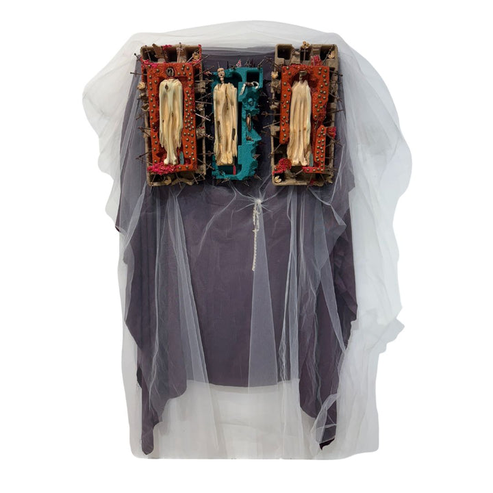 cartons with wooden carved figurines and metal sword crosses sticking out on top purple and white tulle fabric red and blue paint idols