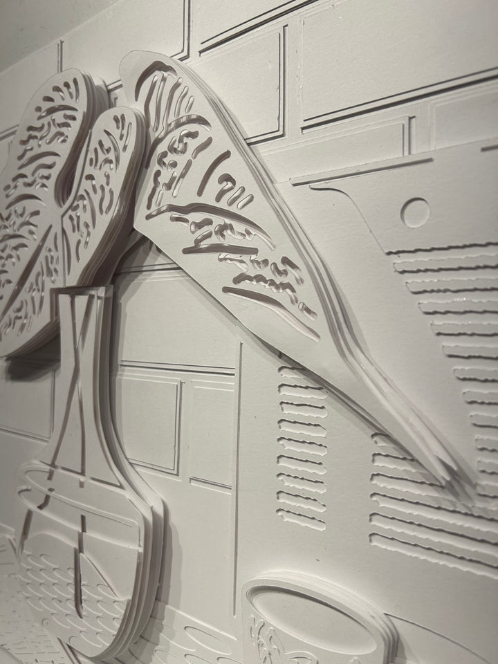 14"x14" layered white paper forming a a vase with leaves on a wall. 