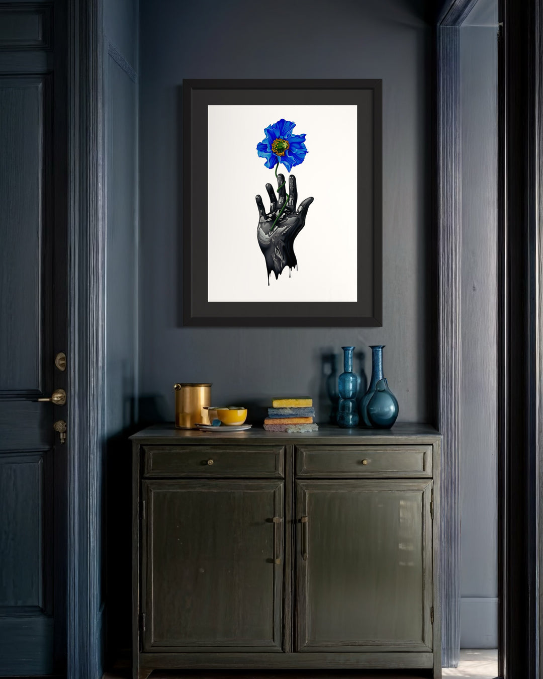 A dripping black hand holds out a vibrant blue poppy flower on a stark white background. The drips on the hand look like black oil, and the flower looks like it&
