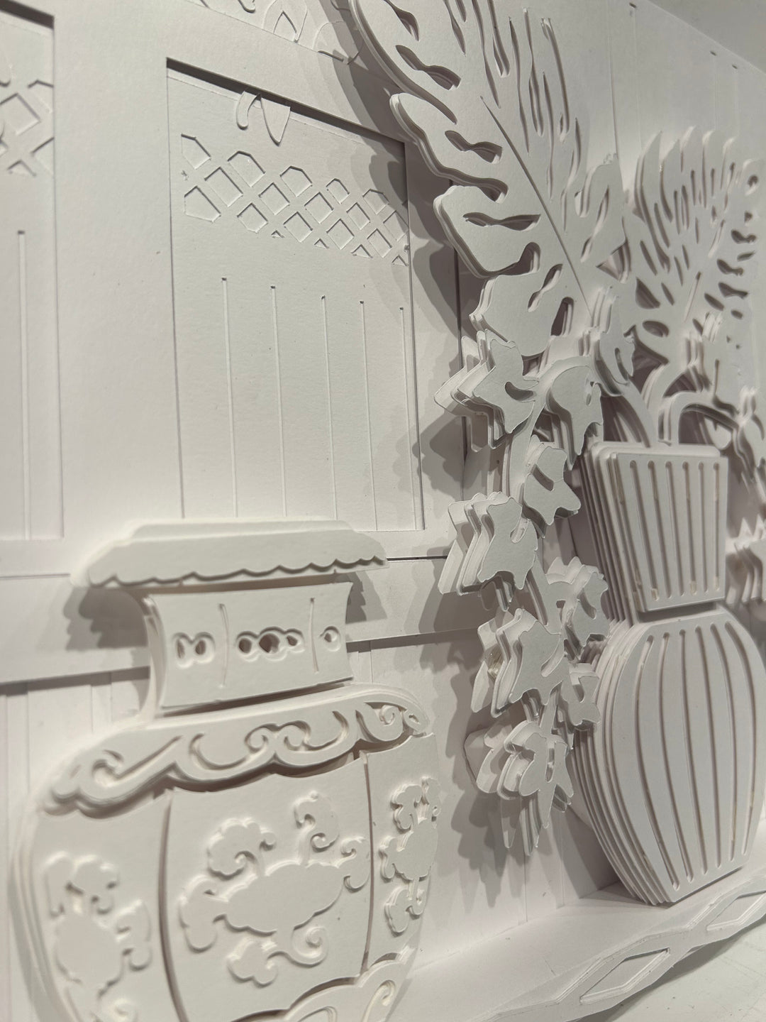 14"x14" layered white paper forming a fern in a striped vase on a wall. 