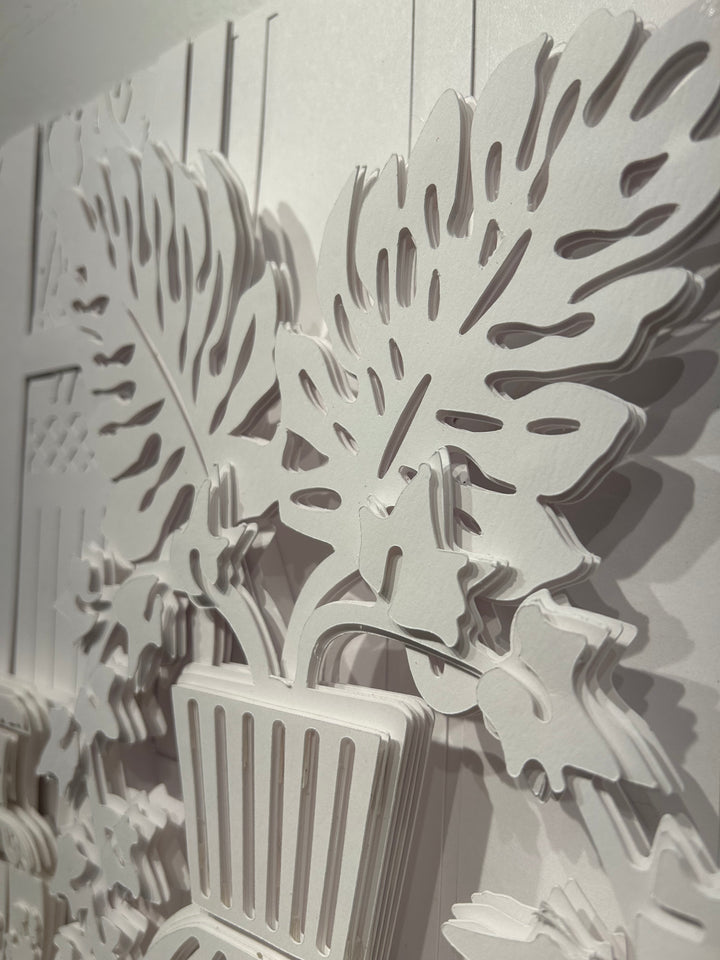 14"x14" layered white paper forming a fern in a striped vase on a wall. 