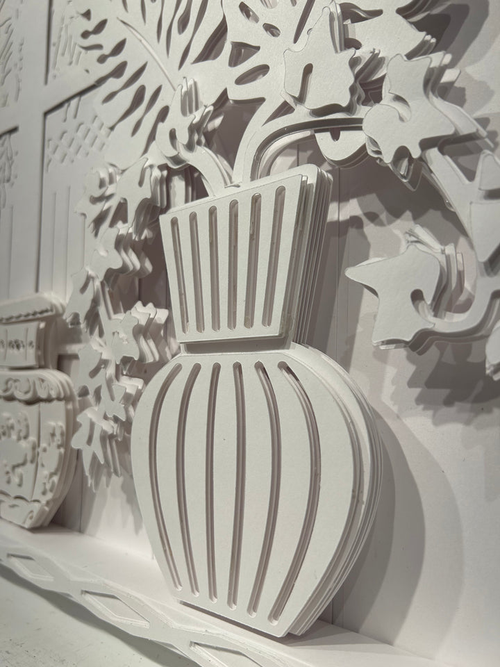 14"x14" layered white paper forming a fern in a striped vase on a wall. 